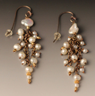 dangling earrings of all white pearls of different sizes.